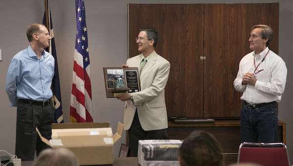 Ed Hughes (left), the district's Formerly Used Defense Site program manager, and Dan Noble (right), project manager for the Spring Valley Formerly Used Defense Site project, presented Lan Reeser with the famous Sgt. Maurer photo and artifacts found at the Spring Valley project.  Lan has worked on Spring Valley since the beginning of the project in 1993.  