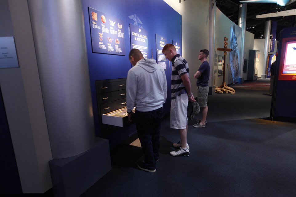 Marines with Headquarters and Headquarters Squadron at Marine Corps Air Station Cherry Point, North Carolina, look at old versions of the Marine Corps ensign the eagle, globe and anchor during a tour of the National Museum of the Marine Corps in Virginia, April 22, 2015.