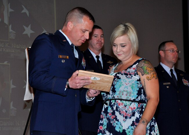 Lt. Col. Rob Rigtrup, 363rd Intelligence, Surveillance, and Reconnaissance Group deputy commander presents Lacie Dickson, wife of SSgt. Richie Dickson, with a personalized plaque and coin at the newly dedicated Independence Hall at Beale Air Force Base, Calif., April 27, 2015. Each family member who represented the fallen Airmen received a coin along with an artist's rendering of the plaque that will be permanently mounted at the entrance of Independence Hall. (U.S. Air Force photo by Airman 1st Class Taylor A. Workman/Released)