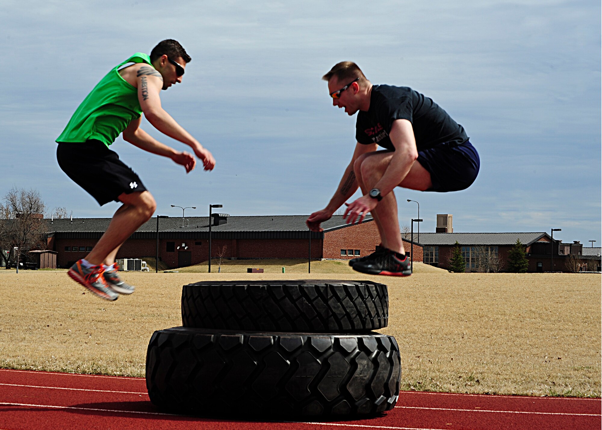 Senior Airman Joshua L. Coonich, 319th Medical Operations Squadron flight medicine medical technician, and Air Force Staff Sgt. Adam Stelmack, 319th Operations Support Squadron NCO in charge of airfield management operations, perform box jumps using tires as a platform April 18, 2015 on Grand Forks Air Force Base, N.D. Coonich and Stelmack are members of a group of Airmen dedicated to training for a Battlefield Airman career field. (U.S. Air Force photo by Airman 1st Class Ryan Sparks/released)