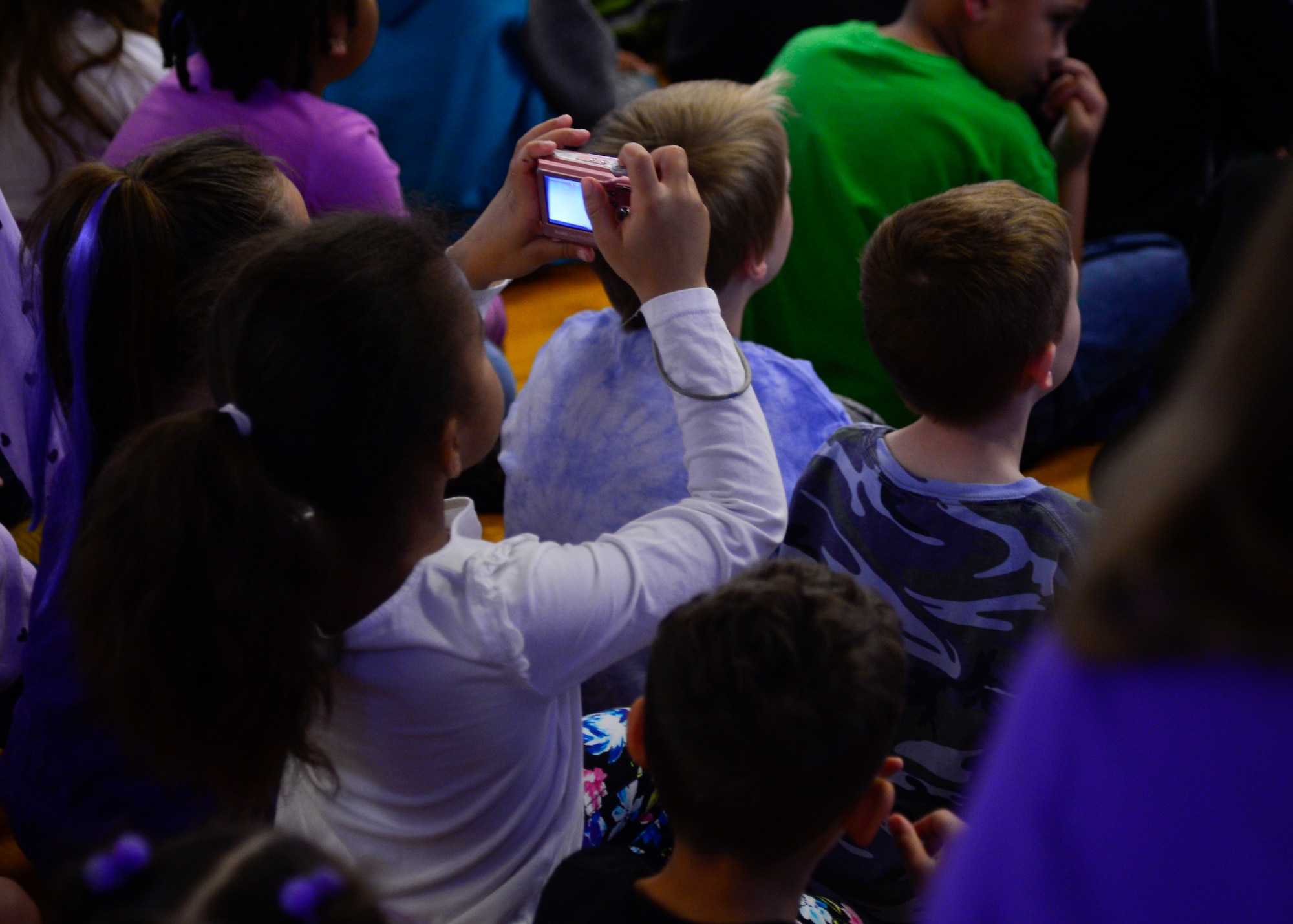 A student from Welch Elementary School takes a picture of a slideshow during the Welch’s Month of the Military Child assembly April 21, 2015, at Welch Elementary School on Dover Air Force Base, Del. A photo slideshow of teachers, staff and family holding sings supporting military kids was played during the assembly. (U.S. Air Force photo/Airman 1st Class William Johnson)