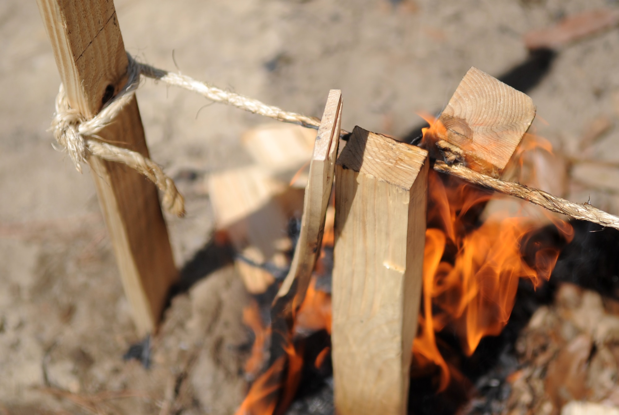 The fire created by a team of “Community Quest” competitors, “The Force,” burns through a rope during a Club Day event, April 24, 2015, at Seymour Johnson Air Force Base, North Carolina. Teams reaching this station in the quest were required to start a fire large enough and hot enough to burn through a length of rope tied above it using only a block of wood, a hatchet and a lighter. (U.S. Air Force photo/Senior Airman Ashley J. Thum)
