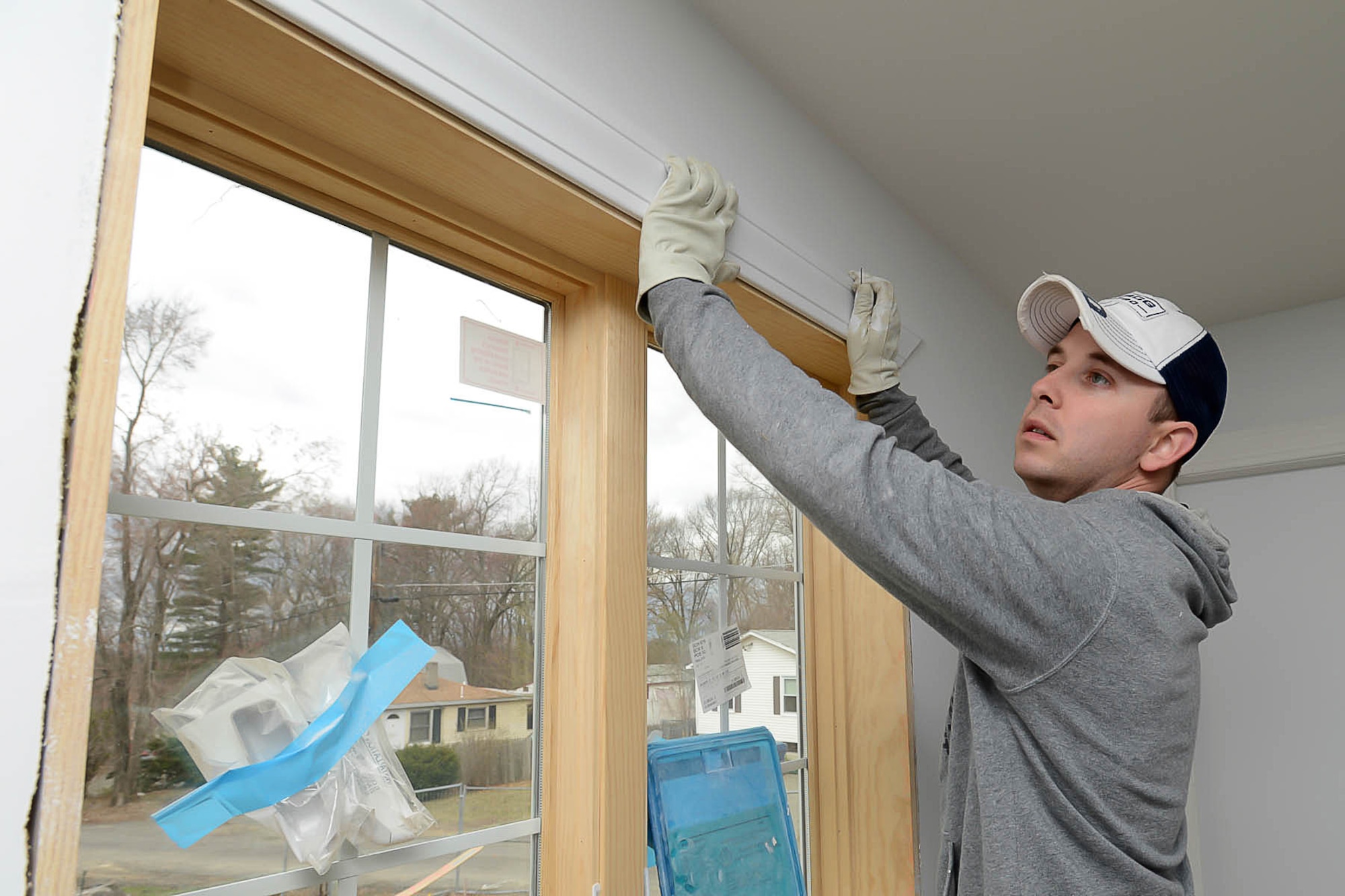 Tech. Sgt. Justin Calvaruzo, Acquisition Intelligence Capabilities, Intelligence NCO in charge, lines up the trimming on a newly installed window frame before nailing it into place during a Habitat for Humanity home construction project April 23. Base volunteers participated in two Habitat for Humanity of Greater Lowell community projects in Billerica, Mass., as part of a Patriot Enlisted Association-led volunteer project. (U.S. Air Force photo by Jerry Saslav)