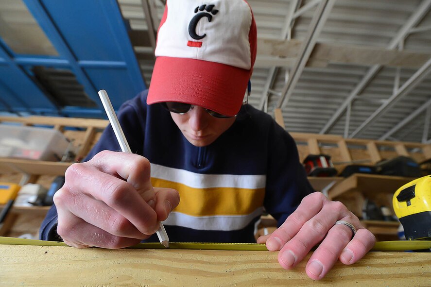 Capt. Brayden Bennett, 66th Medical Squadron Pharmacy Service officer in charge, marks a piece of wood prior to cutting it during a Habitat for Humanity of Greater Lowell community service project April 23.  Some volunteers worked to build a handicap ramp, while others performed work at a handicap-accessible home. (U.S. Air Force photo by Jerry Saslav)