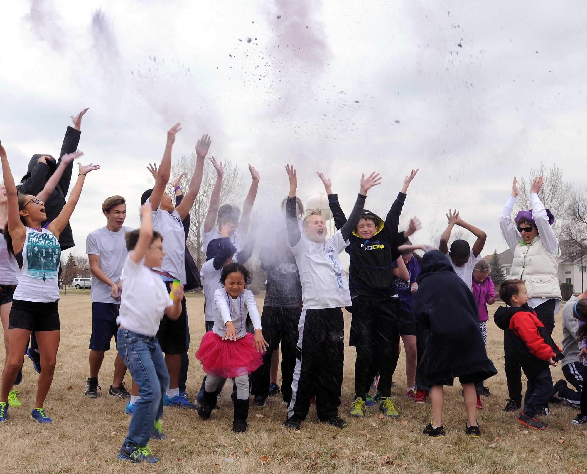 Participants of the Purple Up! fun run on Grand Forks Air Force Base, N.D., throw the remaining powder from the event into the air simultaneously to celebrate the completion of the event on April 24, 2015, which highlighted Month of the Military Child. During MMC, organizations across the military are encouraged to promote events that actively involve military children in a positive manner. (U.S. Air Force Photo by Senior Airman Zachiah Roberson/Released)