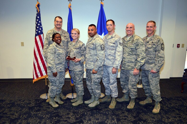 Brig. Gen. Kory Cornum, Air Mobility Command surgeon, presents the Air Mobility Command 2014 Outstanding Small Medical Logistics Account of the Year Award to Capt. Jamie Robinson, Senior Airman Christia Trubee, Master Sgt. Craig Picou and Staff Sgt. Nathan Clark, 43rd Aeromedical Evacuation Squadron, with Col. Kenneth Moss, 43rd Airlift Group commander and Chief Master Sgt. James Cope, 43rd Airlift Group superintendent, during Cornum’s visit to the 43rd Airlift Group on Apr. 22, Pope Army Airfield, N.C. (U.S. Air Force photo/Marvin Krause)