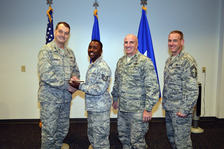 Brig. Gen. Kory Cornum, Air Mobility Command surgeon, presents the Air Mobility Command 2014 Outstanding Enlisted Health Services Management Noncommissioned Officer of the Year Award to Tech. Sgt. Nathan Butler, 43rd Medical Squadron, with Col. Kenneth Moss, 43rd Airlift Group commander and Chief Master Sgt. James Cope, 43rd Airlift Group superintendent, during Cornum’s visit to the 43rd Airlift Group on Apr. 22, Pope Army Airfield, N.C. (U.S. Air Force photo/Marvin Krause)