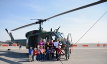 Team Malmstrom families pose in front of a UH-1N Huey during a static display April 22, 2015, at Malmstrom Air Force Base, Mont. Malmstrom Family Child Care, in conjunction with the 40th Helicopter Squadron, hosted the event to teach children more about the helicopter. (U.S. Air Force photo/Airman 1st Class Dillon Johnston)