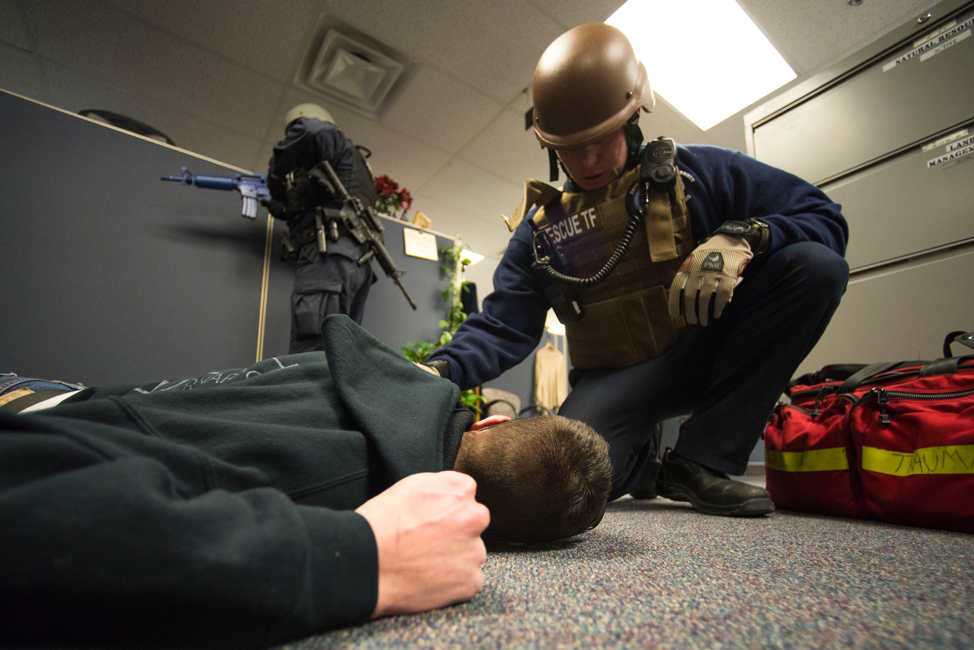 Duane White, 88th Civil Engineer Fire Department captain, checks on a victim portrayed by U.S. Air Force 2nd Lt. Austin Troya, National Air and Space Intelligence Center signals analysis squadron executive officer, during an active shooter exercise, Feb. 5, 2015, at Wright-Patterson Air Force Base, Ohio. Volunteers were moulaged and spread throughout the building to simulate various wounds of an active shooter environment. (U.S. Air Force photo by Wesley Farnsworth/Released)