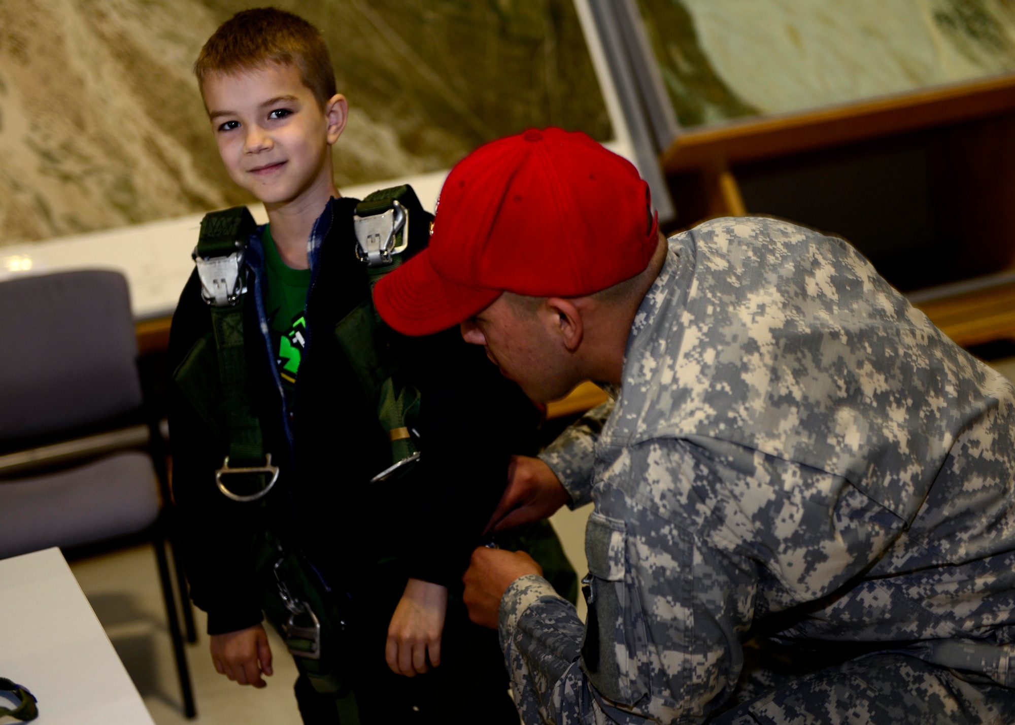 U.S. Army Spc. Lorenzo Jurado, Headquarters and Headquarters Company 173rd Brigade Support Battalion parachute rigger, straps on a parachute to Kyle Martin during a mock deployment, April 27, 2015, at Aviano Air Base, Italy. The students were educated on the different parachutes and riggers procedures. (U.S. Air Photo by Senior Airman Areca T. Wilson/Released)