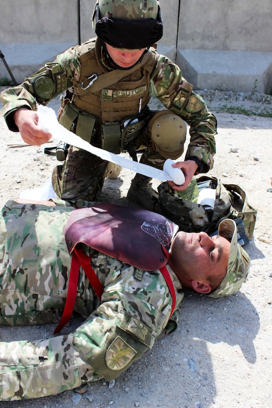 A coalition soldier provides medical aid to a mock casualty during a base defense emergency response exercise on Bagram Airfield, Afghanistan, April 10, 2015.
