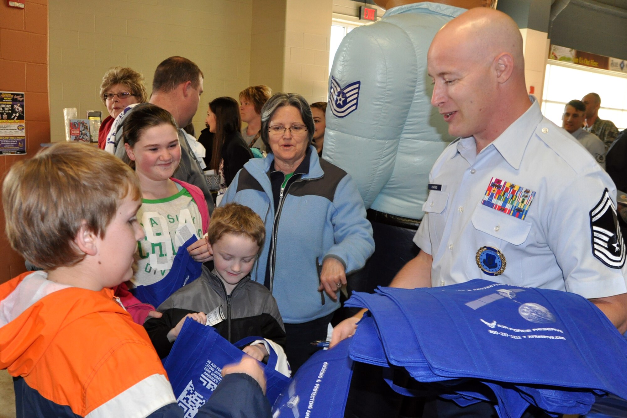 Air Force Reserve Senior Master Sgt. Jerry Harms, Youngstown Air Reserve Station Air Force Reserve Recruiting Flight Chief, hands some USAFR tote bags to young fans near the YARS Recruiting Flight’s display during pre-game festivities for a Youngstown Phantoms hockey game at the Covelli Centre here, April 11, 2015. A group of Citizen Airmen, based at nearby Youngstown Air Reserve Station, Ohio, participated in YARS Night Out activities before and during the game. Prior to the game, the Phantoms, a member of the United States Hockey League, were presented the league’s Anderson Trophy for achieving the most points by a team this season. The Phantoms defeated Team USA 7-1 to complete their regular season in front of a home ice crowd of more than 4000 fans. (U.S. Air Force photo/ Master Sgt. Bob Barko Jr.)