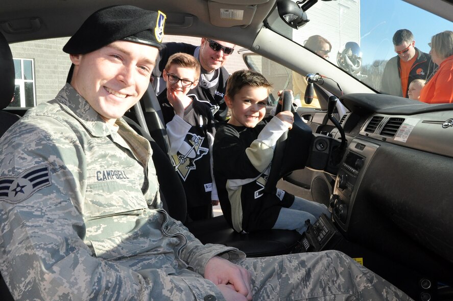 Air Force Reserve Senior Airman Brandon Campbell, a fire team member assigned to 910th Security Forces Squadron, sits with a young fan in a 910th SFS patrol car while the boy’s family looks on outside the Covelli Centre during pre-game festivities for a Youngstown Phantoms hockey game just outside the Covelli Centre here, April 11, 2015. A group of Citizen Airmen, based at Youngstown Air Reserve Station, Ohio, participated in YARS Night Out activities before and during the game including a static display of the patrol car and a concourse display table of 910th SFS equipment. Prior to the game, the Phantoms, a member of the United States Hockey League, were presented the league’s Anderson Trophy for achieving the most points by a team this season. The Phantoms defeated Team USA 7-1 to complete their regular season in front of a home ice crowd of more than 4000 fans. (U.S. Air Force photo/ Master Sgt. Bob Barko Jr.)