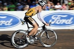 U. S. Army Captain Robert Killian, a signal officer with the 2nd Battalion, 185th Division, Colorado National Guard  speeds by the crowd after transtioning from the water to the bike while competing in the Iron Man Triathlon World Championship on Oct. 9, while at Kona-Kailua, Hawaii.  The grueling race is both a mentally and physically challenging event. The competitors must complete a 2.4 mile swim, followed by a 112 mile bike race and then finish with a 26 mile marathon all in one day. The race takes place Oct. 9 and has more than 1,800 competitors.