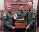 Members of the Idaho Air National Guard’s 190th Fighter Squadron from left to right, Maj. Scott Downey, Lt. Col. Ryan Odneal and Capt. Ryan Brown pose with the trophy that they won during Hawgsmoke 2010 at Gowen Air National Guard Base in Boise, Idaho, Oct. 16, 2010. Missing from the photo, but pictured in a photo cutout, is Maj. Justin Keskey.