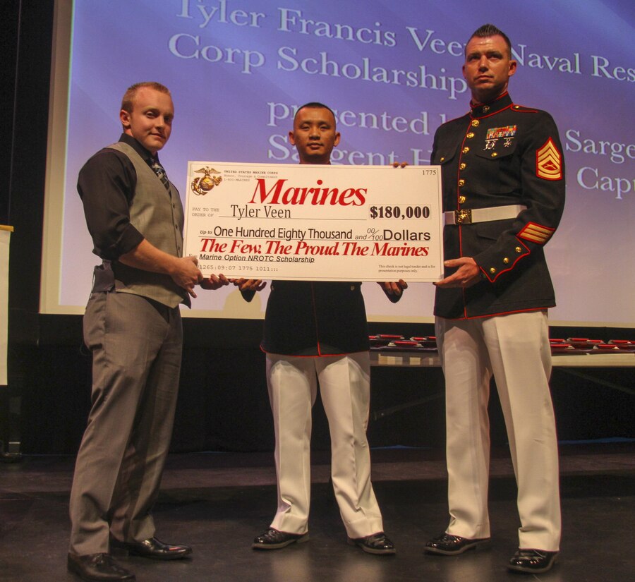 Gunnery Sgt. Gregory Hauk, the station commander for Recruiting Substation Orlando, and Staff Sgt. Nguyen Kim, a canvassing recruiter for Recruiting Substation Orlando, present Tyler Veen, a senior from Lake Highland Preparatory School, Orlando Fl, with the NROTC Check.  Veen is part of a small percentage that receives the opportunity to become Marine Corps officers.