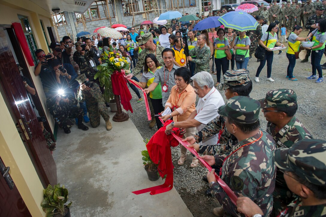 Rosmarie F. Gardose, mayor of Tapaz municipality, and Victor A. Tanco Sr., governor of Capiz province, cut the ceremonial ribbon on a new building at Don Joaquin Artuz Memorial Elementary School in Tapaz, Philippines, during Balikatan 2015, April 27. Armed Forces of the Philippines Army, U.S. Navy and Marine engineers, part of the Combined-Joint Civil-Military Operations Task Force on the island of Panay, worked together for 40 days to complete the Philippine Department of Education, modified one-story, two-classroom building. Balikatan, which means “shoulder to shoulder” in Filipino, is an annual bilateral training exercise aimed at improving the ability of Philippine and U.S. military forces to work together during planning, humanitarian assistance and disaster relief operations. (U.S. Navy photo by Chief Mass Communication Specialist Lowell Whitman/ Released)