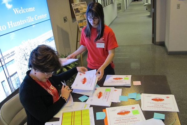 Carmen Perez-De La Matta, Chemical Demilitarization Directorate and daughter Tatiana Ayala take a break from activities to organize student certificates for closing program.