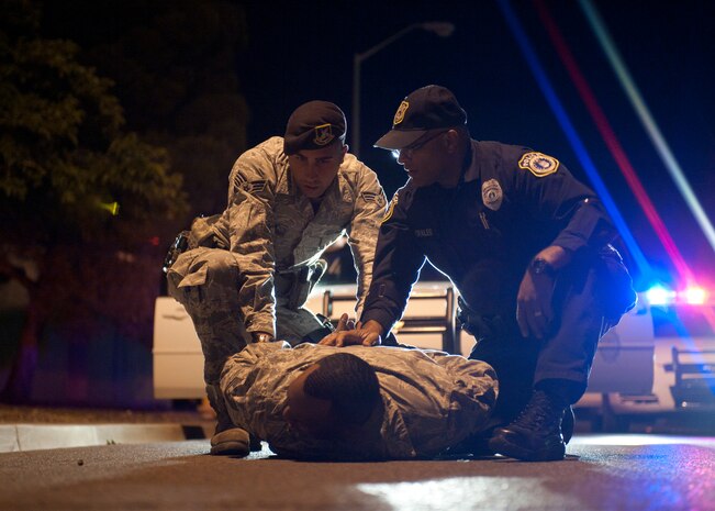 A role player acting as a suspected drunk driver is detained by Senior Airman Daniel Montes and Victor Morales, both 99th Security Forces Squadron patrol leaders, during a drunk driver training exercise at Nellis Air Force Base, Nev., April 27, 2015. Patrolmen are always on the lookout for erratic drivers on Nellis AFB, and are trained for how to swiftly and justly remove them from the roadways. (U.S. Air Force photo by Staff Sgt. Siuta B. Ika)