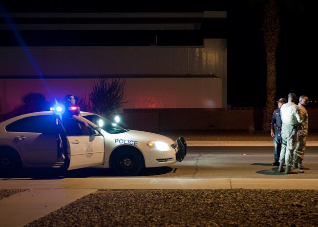 A role player acting as a suspected drunk driver is detained by Senior Airman Daniel Montes and Victor Morales, both 99th Security Forces Squadron patrol leaders, during a drunk driver training exercise at Nellis Air Force Base, Nev., April 27, 2015. Patrolmen are randomly tested by flight leaders on how they respond to different scenarios that could happen during real-world situations. (U.S. Air Force photo by Staff Sgt. Siuta B. Ika)