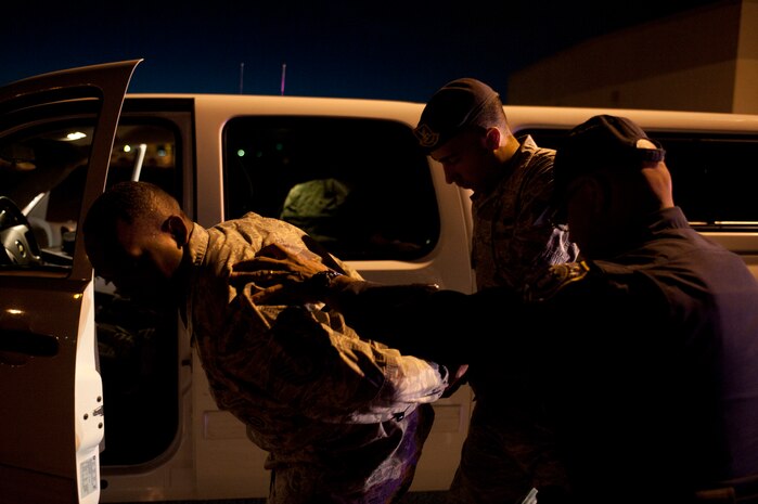 A role player acting as a suspected drunk driver is detained by Senior Airman Daniel Montes and Victor Morales, both 99th Security Forces Squadron patrol leaders, during a drunk driver training exercise at Nellis Air Force Base, Nev., April 27, 2015. Patrolmen are always on the lookout for erratic drivers on Nellis AFB, and are trained for how to swiftly and justly remove them from the roadways. (U.S. Air Force photo by Staff Sgt. Siuta B. Ika)