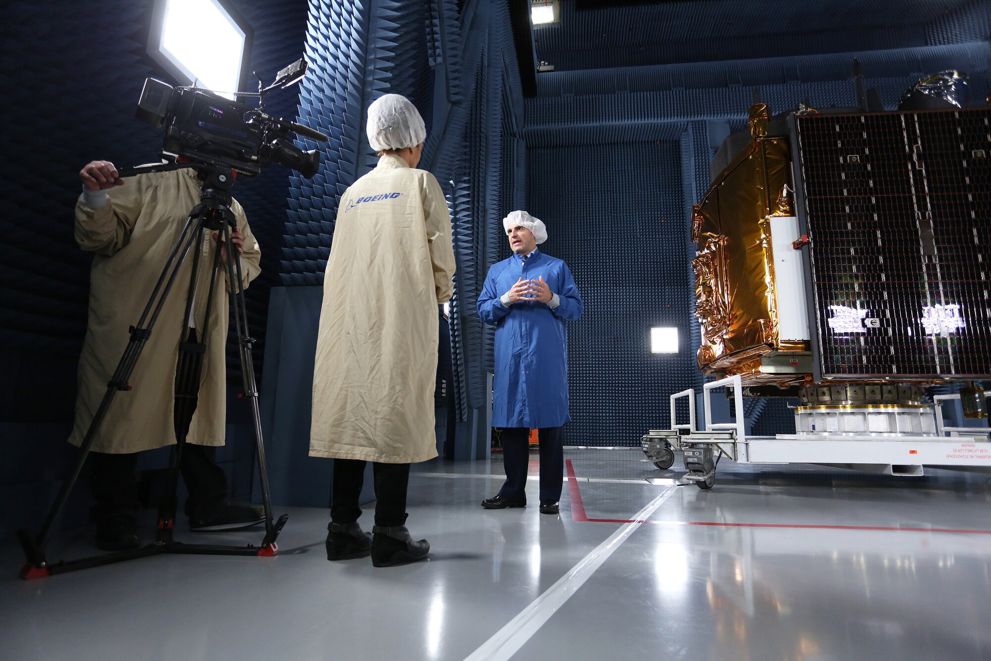 Space and Missile Systems Center video producer Krista Knaus and Cameraman Peter Anninos interview Brig. Gen. Bill Cooley, director of the GPS directorate at SMC, in front of a GPS-IIF satellite at the Boeing facility in El Segundo, California for a behind-the-scenes special about the general's appearance in a CBS/60 Minutes segment on Air Force Space Command that aired April 26, 2015. (Photo by Maj Eric Simon)