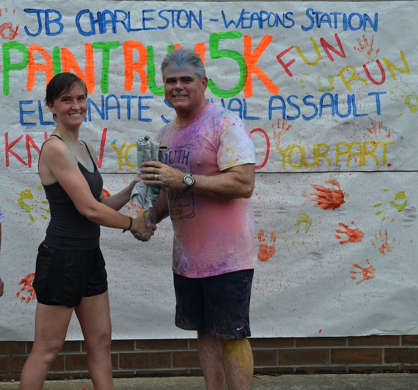 Captain Timothy Sparks, Joint Base Charleston deputy commander congratulates Lt. JG Jennifer Oblinger of Naval Nuclear Power Training Command who came in first place for the women at the Paint Run 5K  Fun Run April 25, 2015 at Joint Base Charleston - Weapons Station, S.C. Oblinger finished with a time of 20:34 for the top female runner.  This free event was open to everyone and was co-hosted by Joint Base Charleston Sexual Assault Prevention and Response Program. April is sexual assault awareness month. This year’s theme is, “Eliminate Sexual Assault: Know your part. Do your part.” The purpose of sexual assault awareness month is to raise awareness about sexual assault prevention and support sexual assault survivors. (Courtesy Photo / Jessica Donnelly) 
