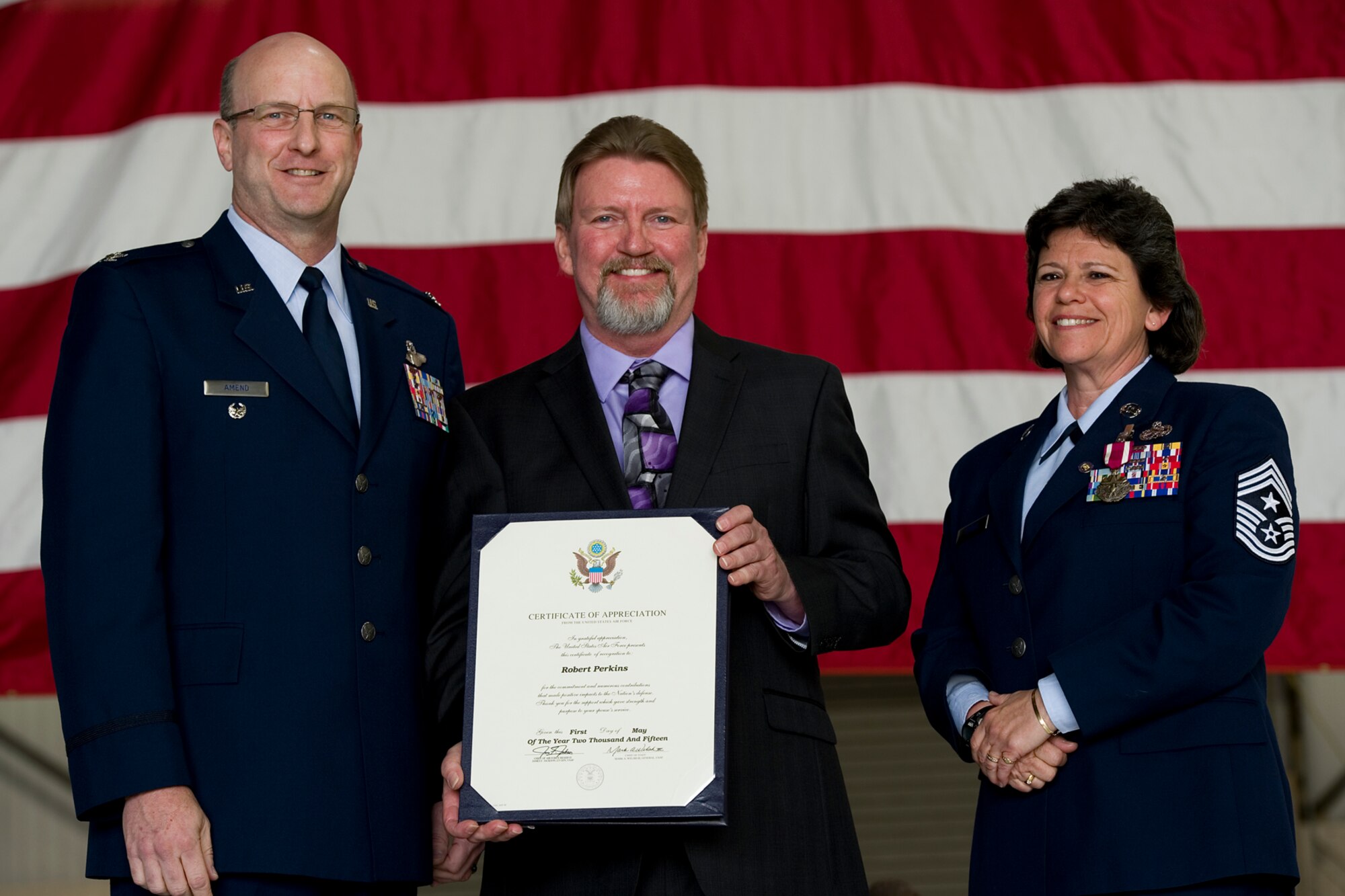 Col. Christopher Amend, Air Mobility Command reserve advisor, poses for a photo after presenting Robert Perkins, a certificate of appreciation, during a retirement ceremony for his spouse, Chief Master Sgt. Karen Perkins, 434th Air Refueling Wing command chief, during her retirement ceremony at Grissom Air Reserve Base, Ind., April 12, 2015. Perkins officially retires from the Air Force Reserve May 1, with over 32 years of service. (U.S. Air Force photo/ Senior Airman Jami K. Lancette)