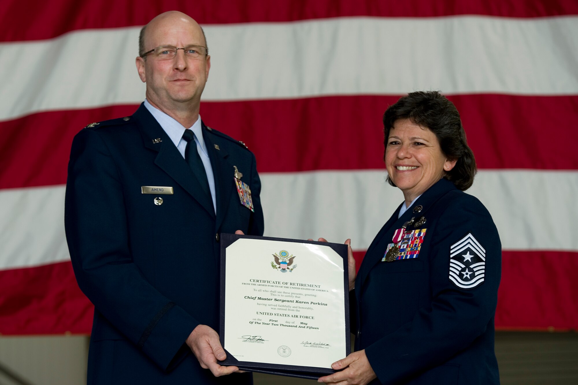 Chief Master Sgt. Karen Perkins, 434th Air Refueling Wing command chief, poses for a photo after receiving her certificate of retirement from Col. Christopher Amend, Air Mobility Command reserve advisor, during her retirement ceremony at Grissom Air Reserve Base, Ind., April 12, 2015. Perkins officially retires from the Air Force Reserve May 1, with over 32 years of service. (U.S. Air Force photo/Senior Airman Jami K. Lancette)