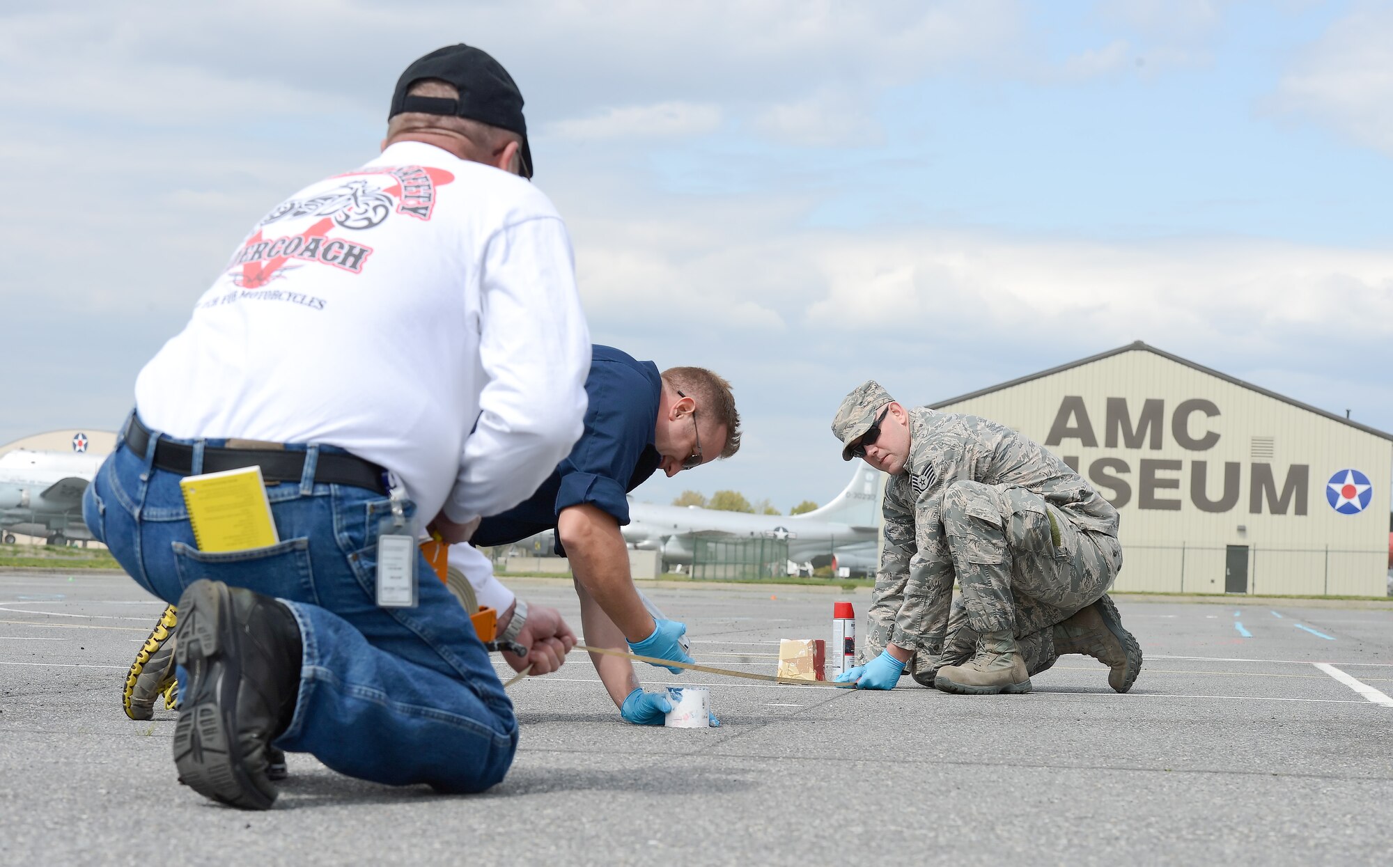 Master Sgt. John Willard, center, 436th Airlift Wing Safety Office, paints new markings on the pavement used for motorcycle safety training on April 27, 2015, at Dover Air Force Base, Del., while Jim Ciolek, Delaware motorcycle program site coordinator and technical representative, left, and Tech. Sgt. Brad Brown, 436th AW Safety Office motorcycle safety program representative, assist. Recent changes to the training curriculum required that new markings be applied to the large parking lot near the Dover FAMCAMP.  (U.S. Air Force photo/Greg L. Davis)