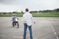 Michael Kyle, motorcycle safety instructor, signals Howard Garcia to slow down during the Basic Rider Course April 24 at the Joint Base San Antonio-Lackland Training Annex. The course is required for all riders who will be riding on an Air Force installation.  (U.S. Air Force photo by Staff Sgt. Marissa Garner)