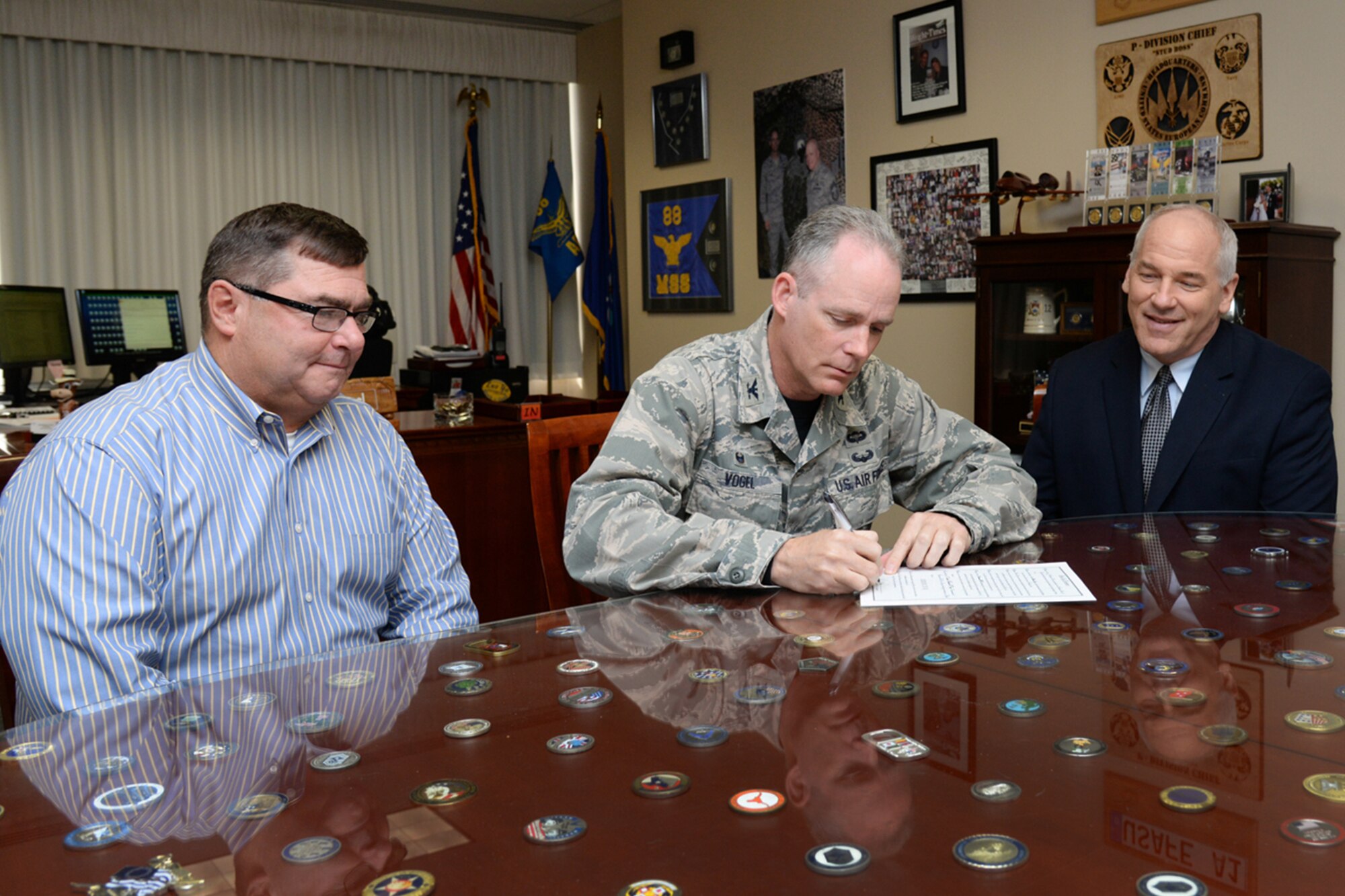 Col. Michael A. Vogel, 66th Air Base Group commander, signs a proclamation declaring April 24 as Arbor Day on base as Thomas Schluckebier, 66 ABG base civil engineer, and Michael Lynch, 66 ABG Portfolio Optimization chief, look on. The proclamation encourages base personnel to support efforts to protect trees, shrubs, woodlands and wetlands for future generations. (U.S. Air Force photo by Linda LaBonte Britt)