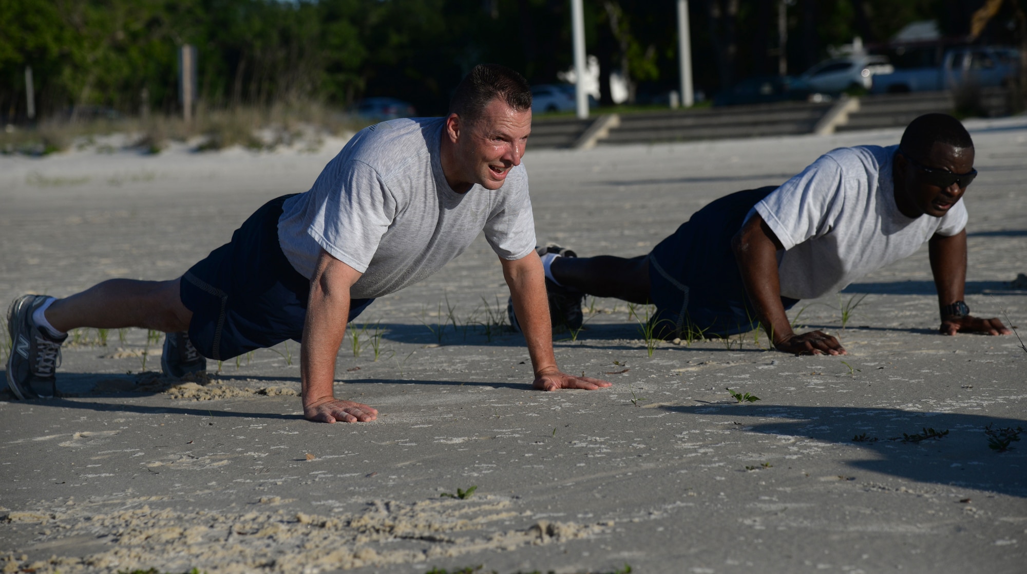 Brig. Gen. Patrick Higby, 81st Training Wing commander, and Chief Master Sgt. Harry Hutchinson, 81st TRW command chief, perform push-ups during the 85th Engineering Installation Squadron’s physical training event at the beach, April 22, 2015, Biloxi, Miss. The 85th EIS invited members from other Keesler units to participate in the 90-minute PT session consisting of a 1.5 mile run and different stations for aerobic exercises. (U.S. Air Force photo by Senior Airman Holly Mansfield)