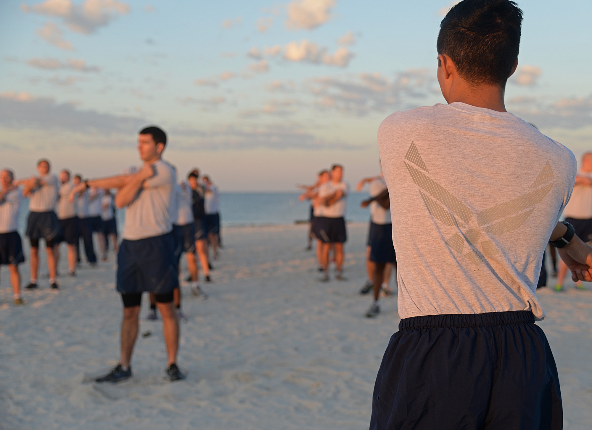 Members of Team Keesler warm up before a physical training event at the beach, April 22, 2015, Biloxi, Miss.  The 85th Engineering Installation Squadron invited other Keesler members to join the 90-minute PT session consisting of a 1.5 mile run and different stations for aerobic exercises. (U.S. Air Force photo by Senior Airman Holly Mansfield)