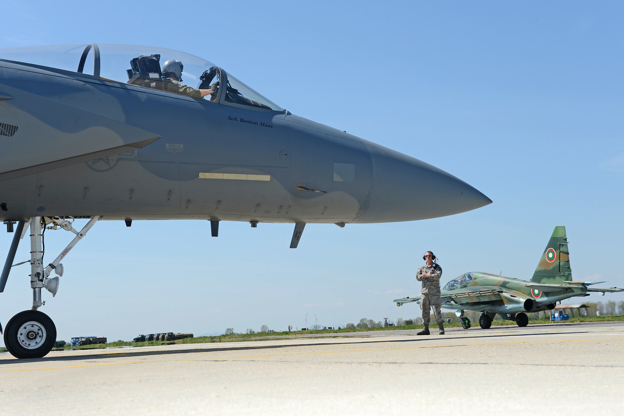 Tech. Sgt. Mark Pittman, F-15 crew chief, 159th Aircraft Maintenance Squadron, Louisiana Air National Guard, holds an F-15 Eagle while a Bulgarian Su-25 Frogfoot taxis past, Apr. 23, 2015, Graf Ignatievo Air Base, near Plovdiv, Bulgaria. Thracian Eagle 2015 is intended to enhance interoperability with Bulgaria and maintain joint readiness with NATO Allies. (U.S. Air National Guard photo by Master Sgt. Toby M. Valadie, 159th Public Affairs Office/Released)
