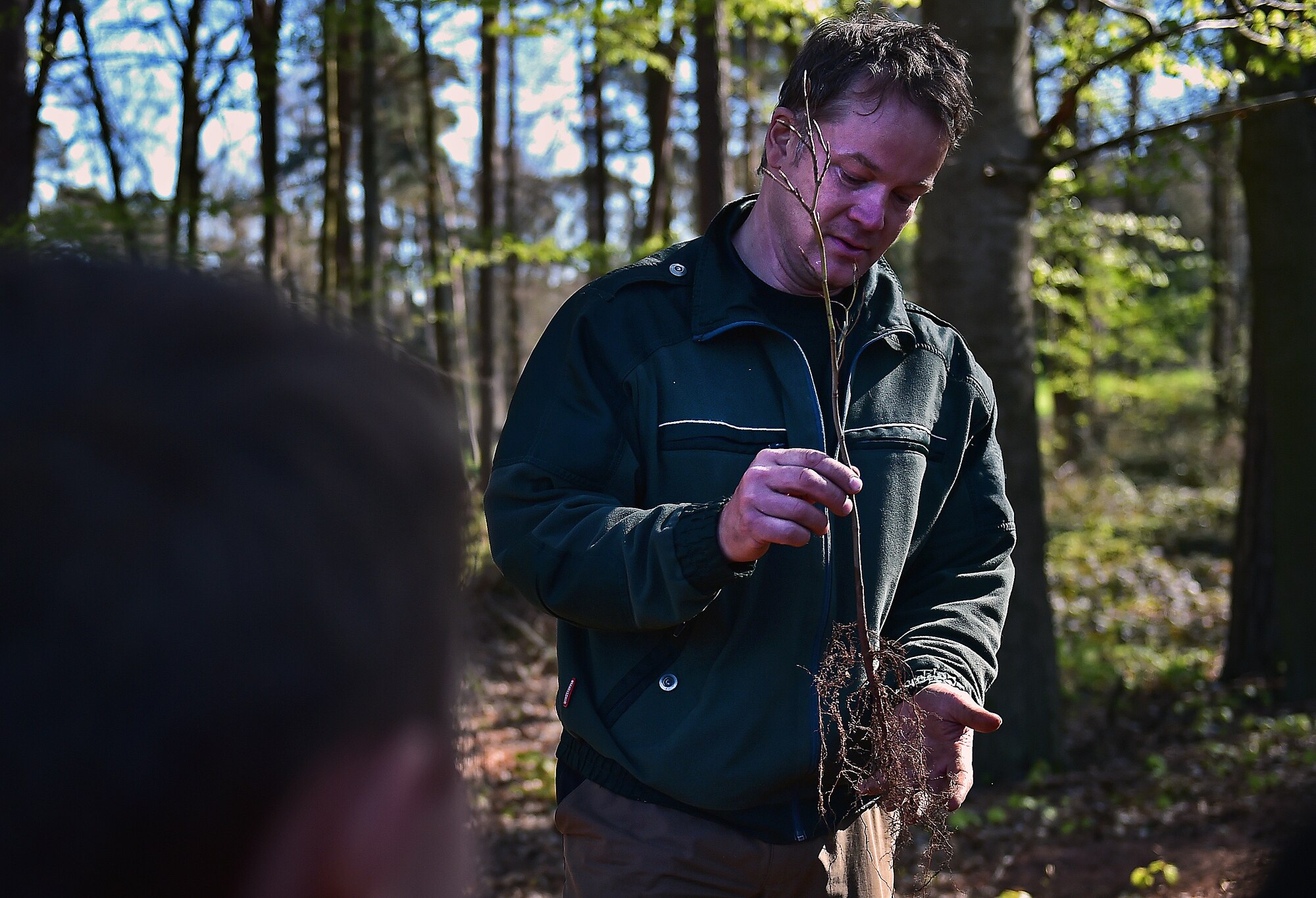 Ulrich Knuff, Ramstein forester, explains the importance of keeping the roots of a young tree moist while re-planting to a group of children from the Ramstein Elementary School April 22, 2015, at Ramstein Air Base, Germany. Knuff helped the group of second graders plant more than 100 trees as part of Earth Day 2015. The class also worked with the Boy and Girl Scouts of the United States of America to clean road borders leading to Ramstein. (U.S. Air Force photo/Staff Sgt. Sara Keller)