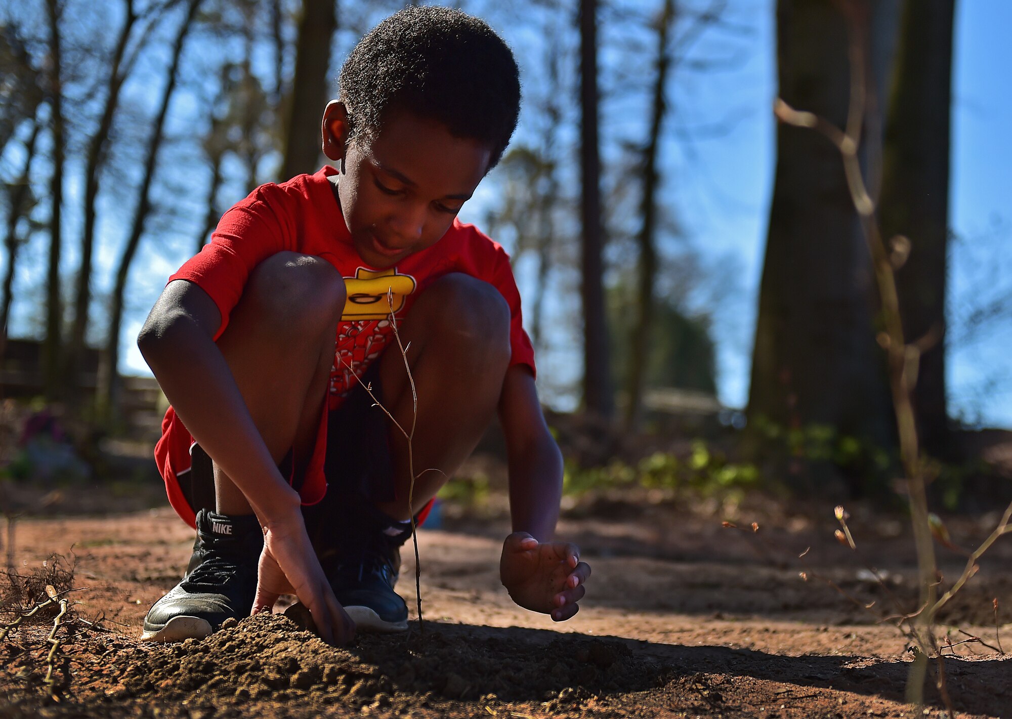 Azarias Porte, second-grade student from Ramstein Elementary School, plants a tree in honor of Earth Day April 22, 2015, at Ramstein Air Base, Germany.  Porte and his classmates worked together to plant more than 100 trees on Ramstein as part of Earth Day 2015. The class also worked with the Boy and Girl Scouts of the United States of America to clean road borders leading to Ramstein. (U.S. Air Force photo/Staff Sgt. Sara Keller)