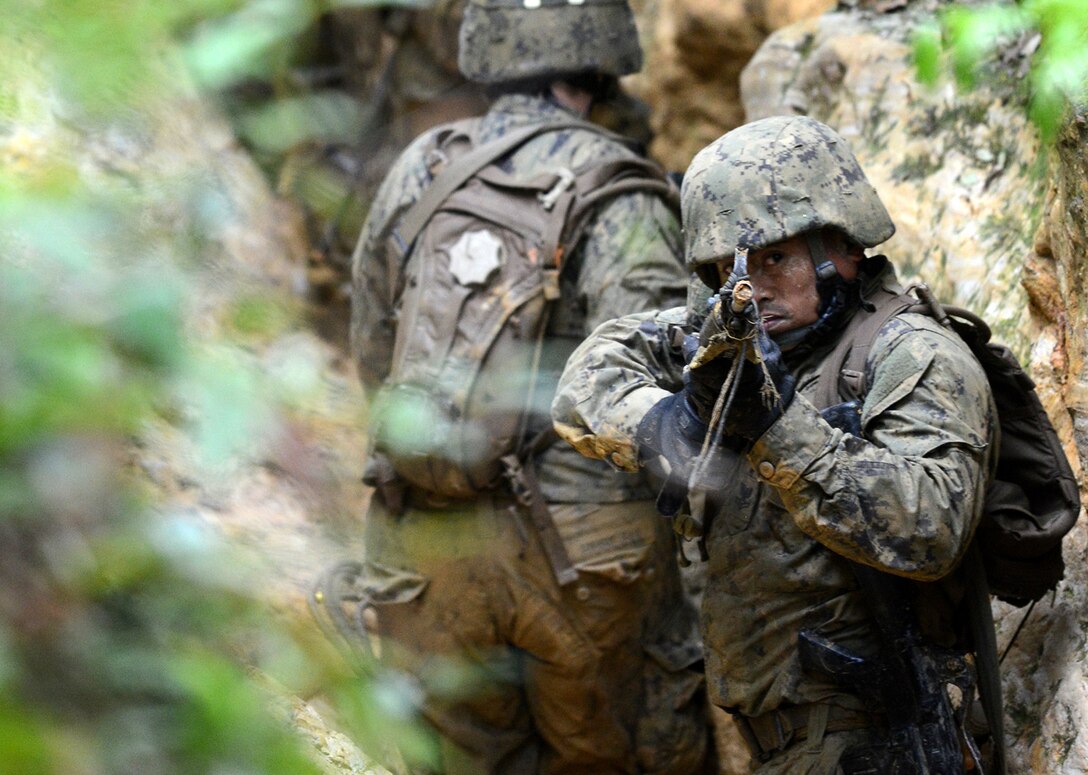 U.S. Navy Petty Officer 2nd Class Elmer Agonias guards the rear of his patrol while other Seabees carry a simulated injured team member on an improvised stretcher through a deep, narrow trench on the Jungle Warfare Training Center in Okinawa, Japan, April 24, 2015. More than 60 Seabees from Naval Mobile Construction Battalion 5 attended the weeklong course taught by Marine instructors. The course is designed to prepare Marines and joint forces for the rigors of combat in a dense jungle environment. NMCB-5 is currently deployed to Japan and several countries in the Pacific area of operations conducting construction operations and humanitarian assistance projects. 