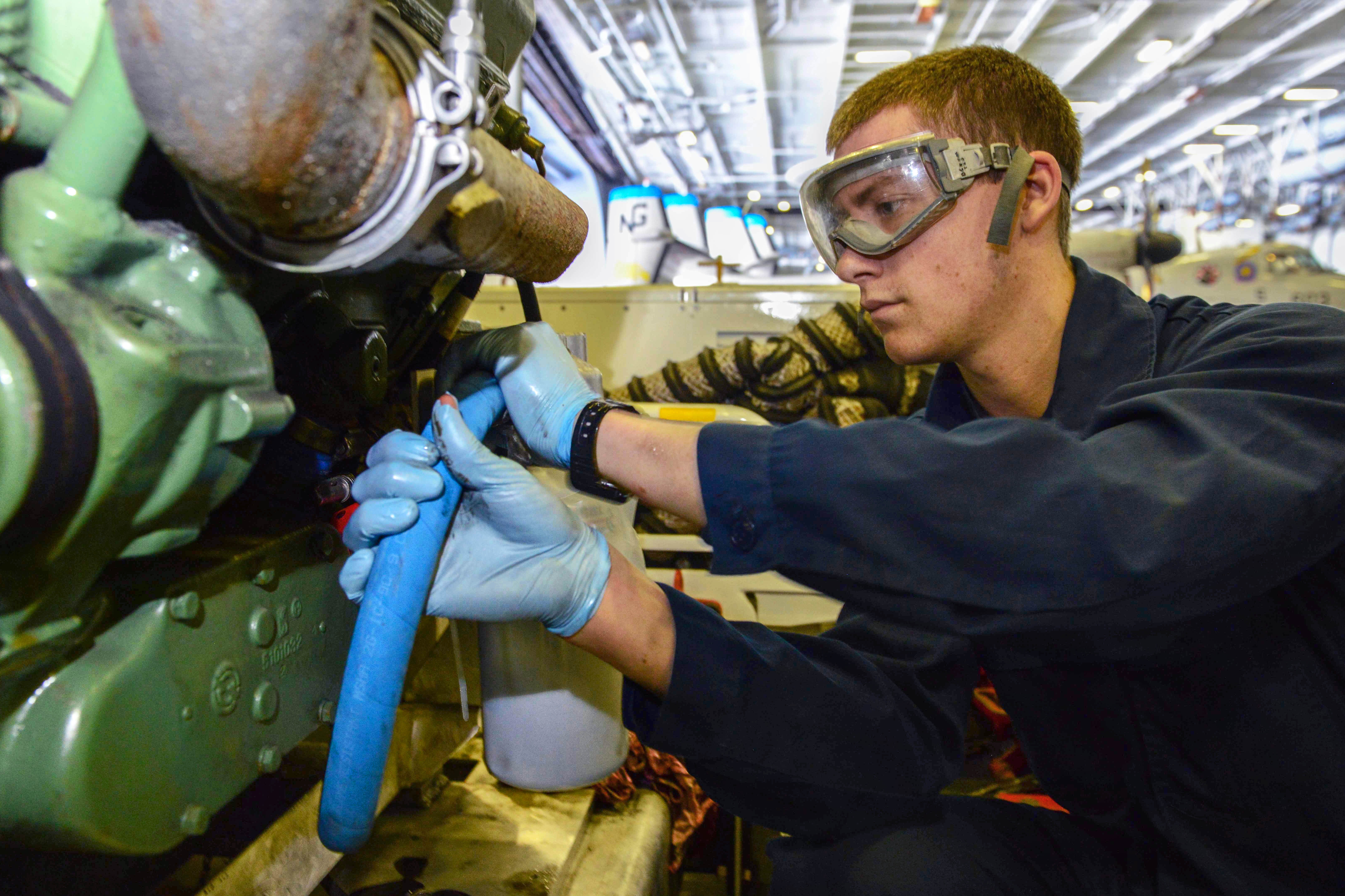 U.S. Navy Seaman Liam Cullen changes oil on a flight deck fire truck ...