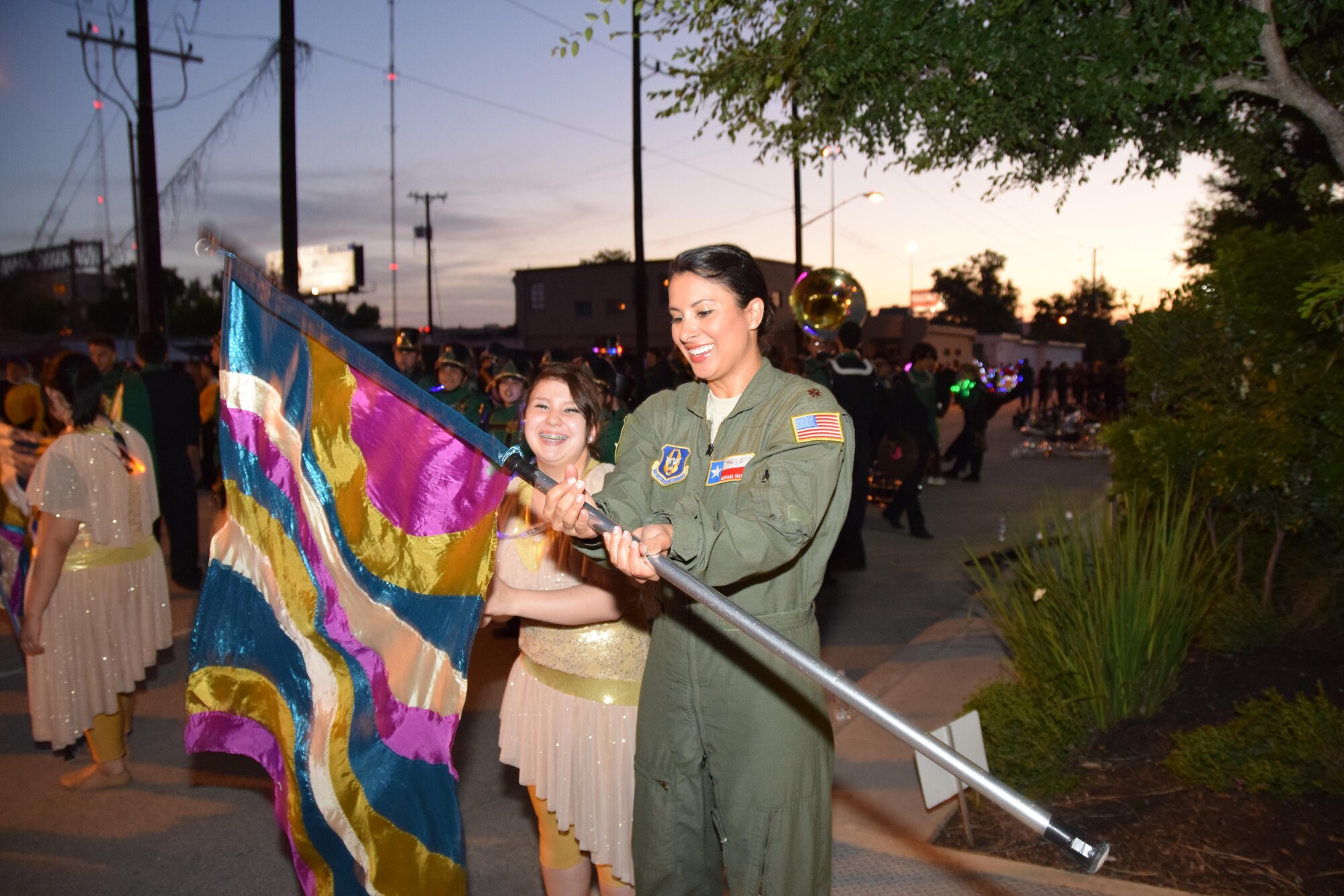 Maj. Adriana Valadez, 433rd Aeromedical Squadron flight nurse, learns how to handle a flag from a member of the Bishop High School Flag Corps prior to the Flambeau Parade in San Antonio, April 25, 2015. The Badger Band and Flag Corps from Bishop, Texas, walked behind the Alamo Wing’s float in the parade. (U.S. Air Force Photo/ Tech. Sgt. Carlos J. Trevino) 
