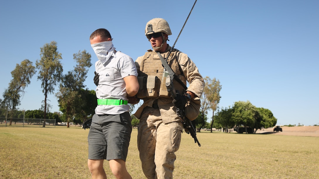 Corporal Christopher Lehring, team leader, 2nd Low Altitude Assault Defense Battalion, 2nd Marine Aircraft Wing, escorts a role-player after detaining him for entering a security perimeter during a foreign humanitarian assistance exercise at Kiwanis Park, Yuma, Arizona, as part of Weapons and Tactics Instructor Course 2-15, April 17. The Role-players acted as foreign locals to provide the Marines with a realistic training scenario as part of their evaluation on handling aggressors, casualties and evacuations. (Official Marine Corps Photo by Cpl. Charles Santamaria/Released)