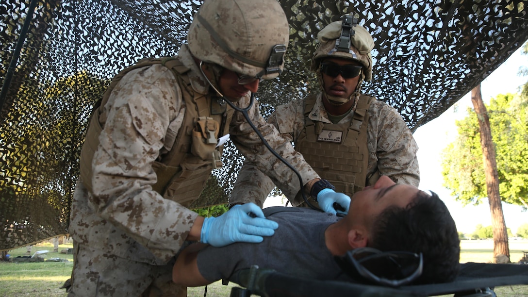 Petty Officer 3rd Class Robert Newkirt (left) and Petty Officer 3rd Class Sebastian Quiceno (right), corpsmen with 1st Battalion, 5th Marine Regiment, check the vitals of a role-player with notional symptoms of concussion at the casualty control point during a foreign humanitarian assistance exercise at Kiwanis Park, Yuma, Arizona, as part of Weapons and Tactics Instructor Course 2-15, April 17. Role-players yelled in pain and pretended to be unconscious, providing a realistic scenario for the evaluated Sailors and Marines during the exercise. (Official Marine Corps Photo by Cpl. Charles Santamaria/Released)