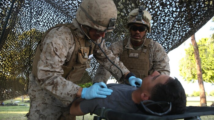 Petty Officer 3rd Class Robert Newkirt (left) and Petty Officer 3rd Class Sebastian Quiceno (right), corpsmen with 1st Battalion, 5th Marine Regiment, check the vitals of a role-player with notional symptoms of concussion at the casualty control point during a foreign humanitarian assistance exercise at Kiwanis Park, Yuma, Arizona, as part of Weapons and Tactics Instructor Course 2-15, April 17. Role-players yelled in pain and pretended to be unconscious, providing a realistic scenario for the evaluated Sailors and Marines during the exercise. (Official Marine Corps Photo by Cpl. Charles Santamaria/Released)