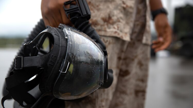 A Marine holds his gas mask after completing leak, seal, package and decontamination training April 21 at the gas chamber on Camp Hansen, Okinawa. Explosive ordnance disposal technicians and chemical, biological, radiological, nuclear defense specialists placed a leaking ordnance package in the gas chamber, using chlorobenzylidene malonitrile, also known as tear gas, to simulate the emission of harmful gases. The EOD technicians and CBRN defense specialists used protective equipment to perform general decontamination of the affected area and prepare the leaking ordnance for safe containment and transport before completing the decontamination process. The training instilled the Marines’ confidence in their safety equipment and procedures used to mitigate CBRN-related hazards. The Marines are with 9th Engineer Support Battalion and Marine Logistics Group Headquarters Regiment, 3rd MLG, III Marine Expeditionary Force.