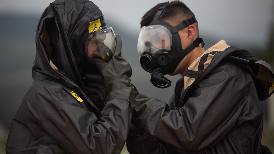 Two chemical, biological, radiological, nuclear defense specialists  ensure gas masks are properly fitted prior to leak, seal, package and decontamination training April 21 at the gas chamber on Camp Hansen, Okinawa. The CBRN defense specialists assisted in familiarizing explosive ordnance disposal technicians with decontamination procedures following the leak, seal, package process used to mitigate CBRN-related hazards.  The EOD technicians and CBRN defense specialists used protective equipment to perform general decontamination of the affected area and prepare the leaking ordnance for safe containment and transport before completing the decontamination process. The training instilled the Marines’ confidence in their safety equipment and procedures used to mitigate CBRN-related hazards. The Marines are with 9th Engineer Support Battalion, and Marine Logistics Group Headquarters Regiment, 3rd MLG, III Marine Expeditionary Force.