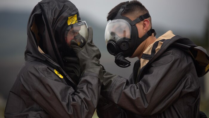 Two chemical, biological, radiological, nuclear defense specialists  ensure gas masks are properly fitted prior to leak, seal, package and decontamination training April 21 at the gas chamber on Camp Hansen, Okinawa. The CBRN defense specialists assisted in familiarizing explosive ordnance disposal technicians with decontamination procedures following the leak, seal, package process used to mitigate CBRN-related hazards.  The EOD technicians and CBRN defense specialists used protective equipment to perform general decontamination of the affected area and prepare the leaking ordnance for safe containment and transport before completing the decontamination process. The training instilled the Marines’ confidence in their safety equipment and procedures used to mitigate CBRN-related hazards. The Marines are with 9th Engineer Support Battalion, and Marine Logistics Group Headquarters Regiment, 3rd MLG, III Marine Expeditionary Force.