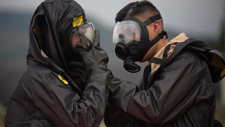 Two chemical, biological, radiological, nuclear defense specialists  ensure gas masks are properly fitted prior to leak, seal, package and decontamination training April 21 at the gas chamber on Camp Hansen, Okinawa. The CBRN defense specialists assisted in familiarizing explosive ordnance disposal technicians with decontamination procedures following the leak, seal, package process used to mitigate CBRN-related hazards.  The EOD technicians and CBRN defense specialists used protective equipment to perform general decontamination of the affected area and prepare the leaking ordnance for safe containment and transport before completing the decontamination process. The training instilled the Marines’ confidence in their safety equipment and procedures used to mitigate CBRN-related hazards. The Marines are with 9th Engineer Support Battalion, and Marine Logistics Group Headquarters Regiment, 3rd MLG, III Marine Expeditionary Force.