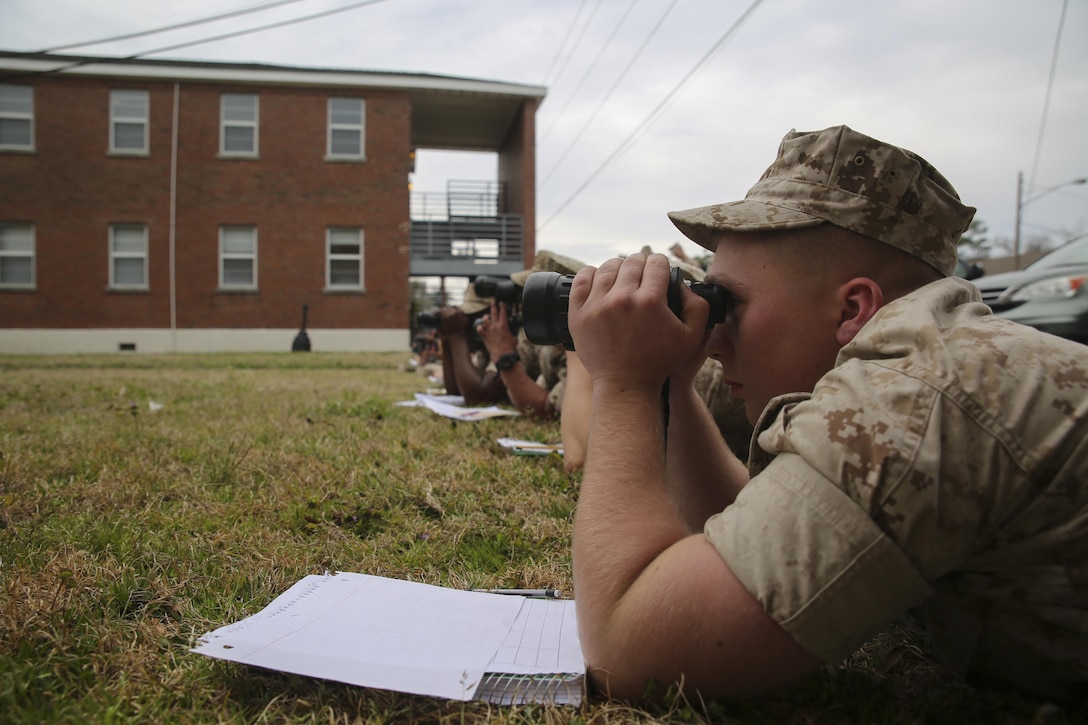 A Marine with II Marine Expeditionary Force uses binoculars to search for practice targets set by the course instructors at the Division Combat Skills Center aboard Camp Lejeune, N.C., March 9, 2015. Training to develop a better understanding of how to locate, identify and describe targets in detail is vital to Marines in the designated marksman role. Ten targets of different sizes, shapes and colors were placed in an open lot for the Marines to locate and exercise their identification skills.