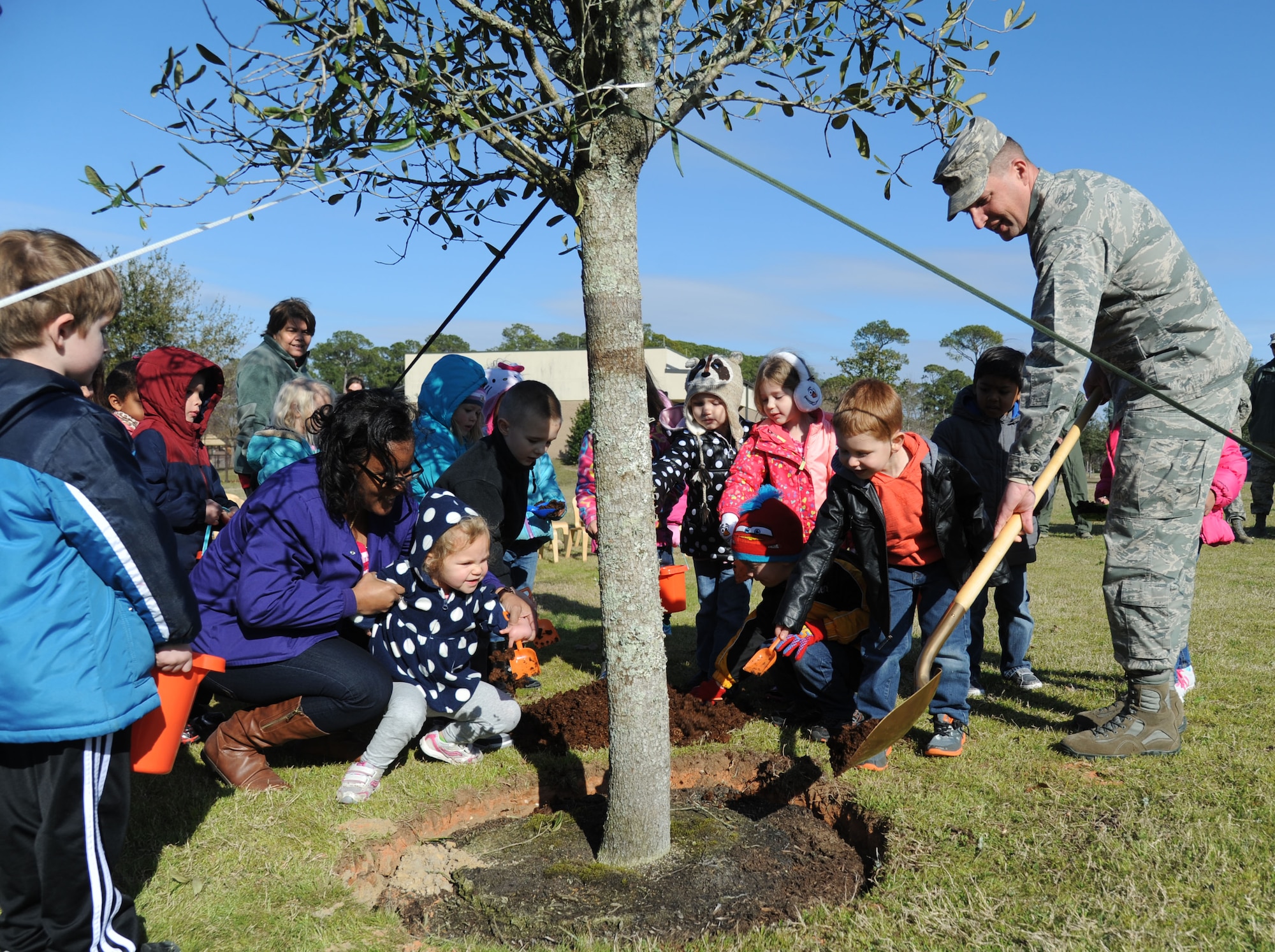 Brig. Gen. Patrick Higby, the 81st Training Wing commander, receives help from children from the child development center with planting a live oak tree outside of the CDC during an Arbor Day celebration Feb. 19, 2015, at Keesler Air Force Base, Miss. Higby, who grew up in Germany, appreciates the education and opportunities he had as a military child. (U.S. Air Force photo/Kemberly Groue)