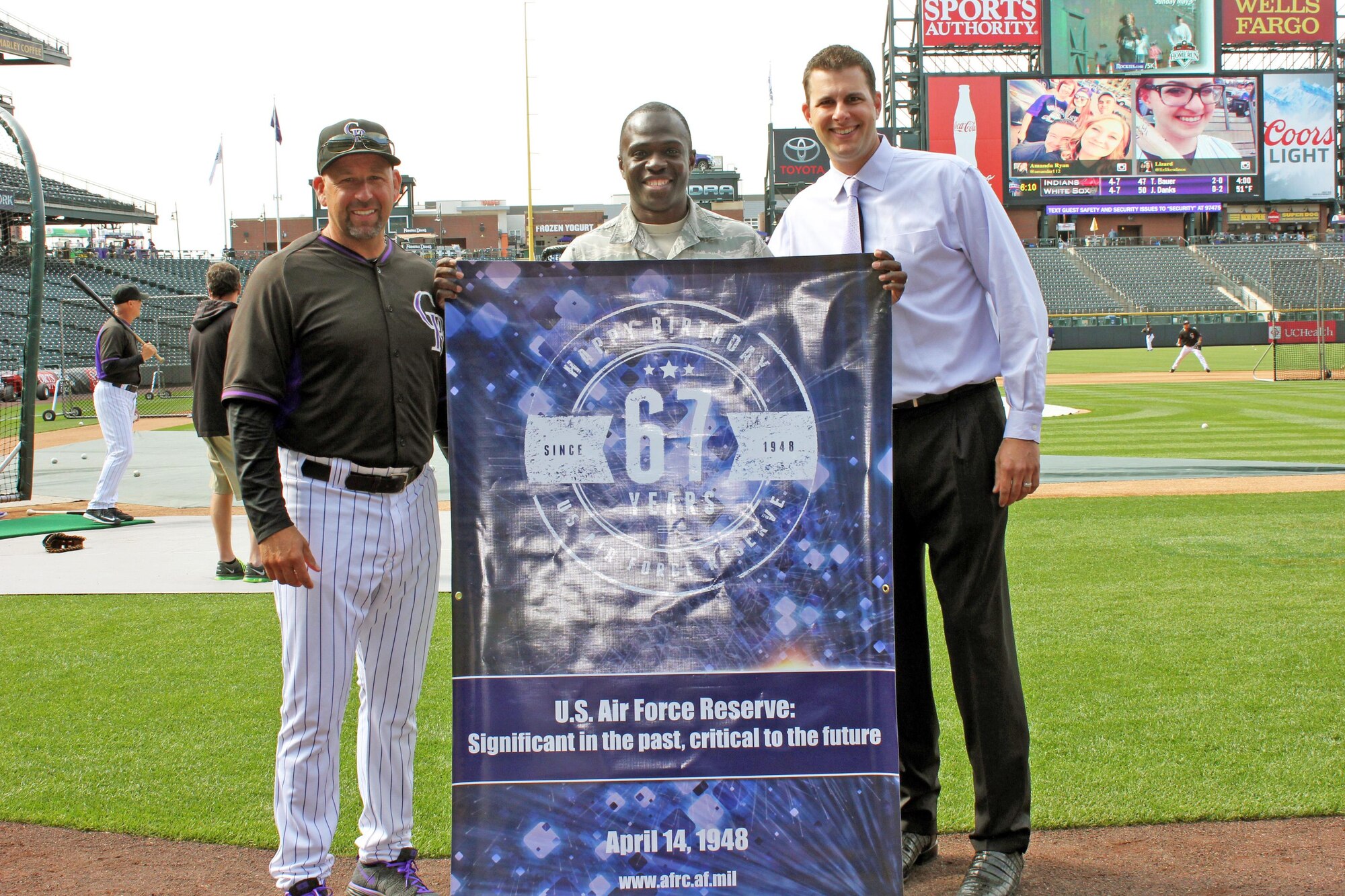 In honor of the Air Force Reserve's 67th anniversary, Air Reserve Personnel Center took photos with a comemorative banner at various events. Senior Airman Evan Joacin stands with members of the Colorado Rockies, April 20, 2015, at Coors Field near downtown Denver. (U.S. Air Force photo/Senior Airman Evan Van Horn)